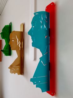 three different colored paper cutouts are hanging on the wall