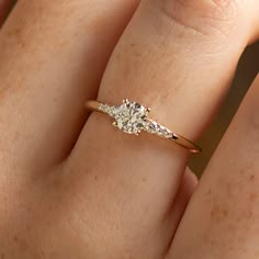 a woman's hand with a diamond ring on top of her finger and the other hand holding an engagement ring