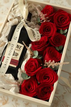 a bottle of wine in a box with red roses