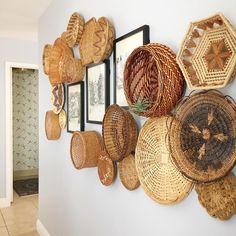 there are many baskets hanging on the wall in this room with pictures and framed photos