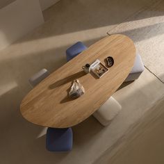 a wooden table with two blue chairs and a shell on the top, in an empty room