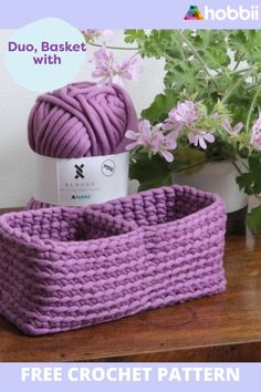 a purple basket sitting on top of a wooden table next to a potted plant