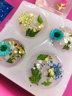 four plates with flowers painted on them sitting on a table