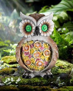 an owl statue with green eyes and flowers