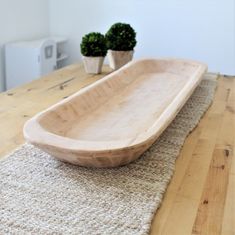 a wooden bowl sitting on top of a rug next to two potted planters