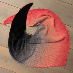 an orange and black scarf laying on top of a wooden floor