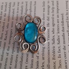 Very beautiful vintage art nouveau dress brooch. It has a striking turquoise blue cabochon at its centre  turquoise. It is set in a very art nouveau style swirling silver tone frame.  Definitely a statement piece. It will look fabulous on a scarf, coat or evening dress.   4.5 cm x 4 cm x 0.5 cm with trombone clasp which looks a bit twisted but works fine !! Price includes tracked shipping. Art Deco Blue Brooches For Gifts, Art Deco Blue Brooches As Gifts, Blue Cabochon Brooch For Formal Occasions, Antique Handmade Blue Brooches, Formal Blue Cabochon Brooch, Formal Blue Handmade Brooches, Unique Blue Brooches For Formal Occasions, Turquoise Cabochon Brooch For Gift, Turquoise Cabochon Brooch As A Gift