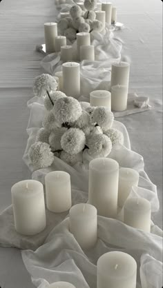 a long table with white candles and flowers on top of it in black and white