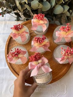 a person is holding a cupcake with pink bows on it in front of some flowers