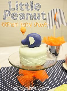 a little peanut elephant baby shower cake on a table with blue and white polka dots