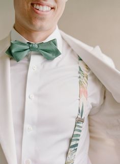 a man wearing a white shirt and green bow tie with palm leaves on his lapel