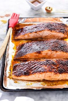 three salmon fillets are on a baking sheet