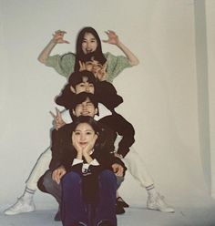 a group of people sitting on top of each other in front of a white wall