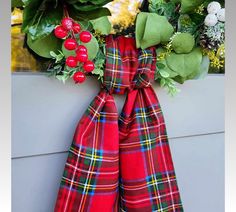 a christmas wreath with red berries and greenery hanging on the side of a building