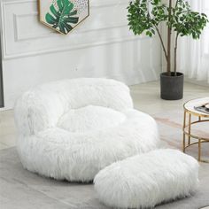 a living room with white fur furniture and a potted plant on the side table