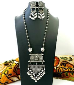 German silver Indian pendant necklace with Taj Mahal in 3D, and a beautiful geometric pendant with faux pearl dangling ghungroo. In a soft grey color with the patina of a vintage piece. Realistic faux pearls Excellent quality and craftsmanship. Necklace measures 12 inch drop. Pendant measures 4.5 inches by 3 inches. View more necklaces here: https://www.etsy.com/shop/BoutiqueByMaryam?section_id=21694658 Be sure to visit the rest of my shop here: https://www.etsy.com/shop/boutiquebymaryam Navratri Bracelet Handmade, Festive Silver Necklace With Pearl Pendant, Traditional White Necklace With Oxidized Finish, Traditional Silver Jewelry With Pearl Pendant, Traditional White Oxidized Finish Necklace, Traditional White Necklaces With Oxidized Finish, Bohemian White Necklaces With Latkans, White Bohemian Necklaces With Latkans, Traditional White Metal Necklace