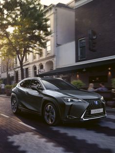 a silver car driving down a street next to tall buildings with trees in the background