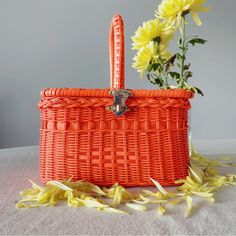 an orange basket with yellow flowers in it