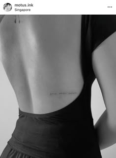 the back of a woman's neck with an inscription on her lower back tattoo