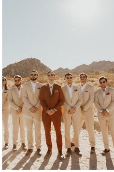 a group of men standing next to each other in front of mountains and sand dunes