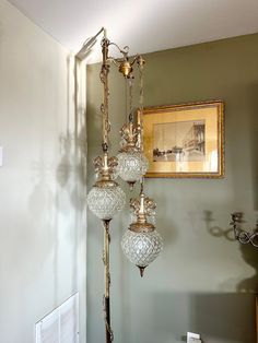 three glass globes are hanging from a gold pole in the corner of a room