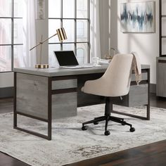 an office desk with a laptop on it in front of a large window and rug