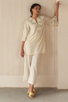 Off-white pure cotton woven short tunic with floral and cross stitch embroidery. Comes with pant.
Components: 2
Pattern: Embroidered
Type Of Work: Woven, Floral, Cross stitch
Neckline: Notched
Sleeve Type: Flared Sleeves
Fabric: Pure Cotton
Color: Off White
Other Details: 
Side slits on tunic
Occasion: Mehendi and Haldi - Aza Fashions Short Kurti Patterns Cotton, White Short Kurti Designs, Short Kurti And Pants, Short Tunics For Women, Kurta Designs Women Casual Cotton, Short Kurta Designs Women, White Short Kurti, Indian Short Kurti, Tunics For Women Indian