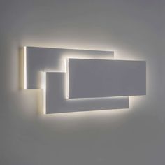 a white wall mounted light with two square lights on it's side and one rectangular light in the middle