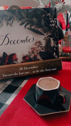 a cup of coffee sitting on top of a table next to a sign that says december