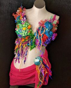 a mannequin wearing a colorful dress with flowers on it's chest and headpieces