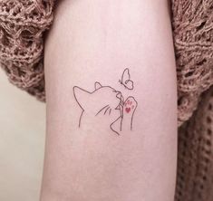 a woman's arm with a small tattoo of a cat and a heart on it