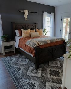 a bedroom with a bed, rug and cow skull mounted on the wall above it