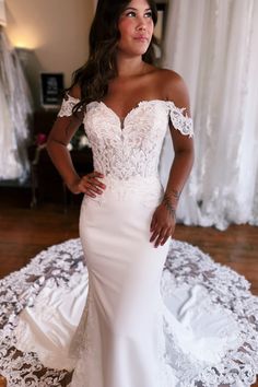 a woman in a white wedding dress posing for the camera with her hands on her hips