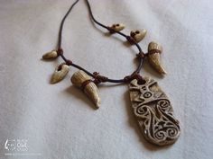 a necklace with an owl and some small beads on the end is adorned with brown cord