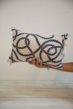 a hand holding a decorative pillow in front of a white wall