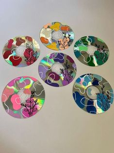 four cd's with different designs on them sitting next to each other in front of a white wall