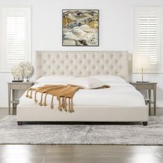 a large white bed sitting on top of a wooden floor next to two nightstands