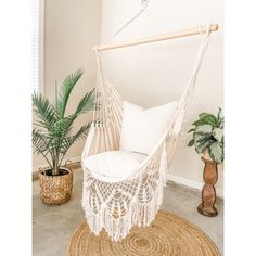 a white hammock chair sitting on top of a rug next to a potted plant