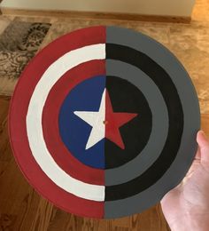 a hand holding a paper plate with an image of the captain's shield on it