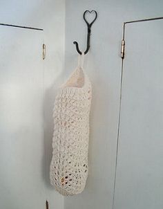 a white crocheted bag hanging from a hook on the wall next to two doors