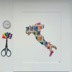 a cut out of the shape of italy with scissors next to it on a white surface