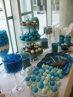 a table topped with lots of blue and white cupcakes