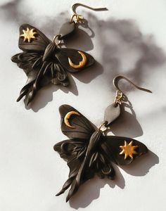 two black and gold butterfly shaped earrings on a white surface