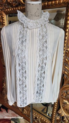 This gorgeous blouse is from the 70's by Designer Oscar de la Renta.  Made of a beige silk and lace. Flat pleats down the front with beautiful white lace insets and collar.  Buttons up the back and cuffs. Full sleeves with button cuffs. Very luxurious. The size has worn away on the tag, however, the best fit would be Large.  Please see the measurements below for a proper fit.  All sales are final. Measurements Armpit-armpit doubled 42" Shoulder 16" Sleeves 24" Length 24" Elegant Lace Top For Day, Elegant Lace Work Blouse For Daywear, Elegant Lace Patchwork Blouse For Daywear, Classic Lace Blouse, Elegant Silk Blouse With Lace Trim, Elegant Beige Lace Top With Lace Sleeves, Feminine Formal Blouse With Lace Work, Elegant Cream Lace Top With Patchwork, Feminine Lace Blouse For Formal Occasions