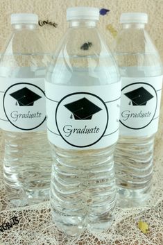 three water bottles with graduation caps on the top and one has a sticker that says graduate