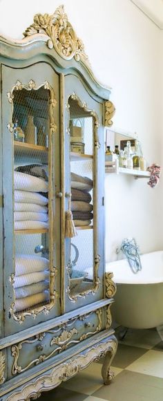 an antique china cabinet in a bathroom with a claw foot bathtub and toilet behind it