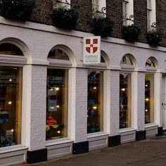 a row of store fronts on the side of a building with arched windows and flower boxes