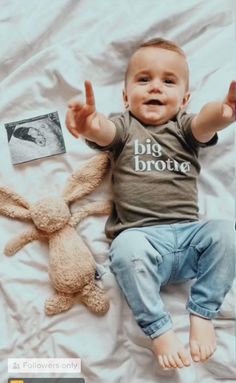 a baby laying on top of a bed next to a stuffed animal and two photos