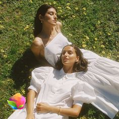 two women laying on the ground in white dresses