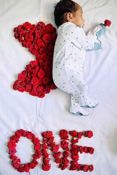 a baby laying on top of a bed covered in red flowers next to the word love